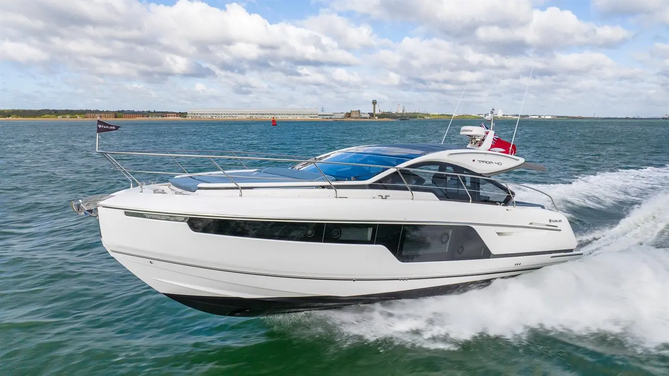A sleek white motorboat cruising on a blue ocean with waves, showcasing a sunny sky and distant land in the background.